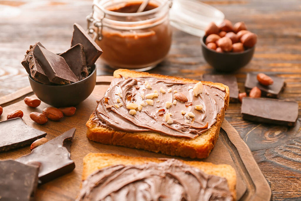Board with fresh bread and chocolate paste on table - Photo, Image