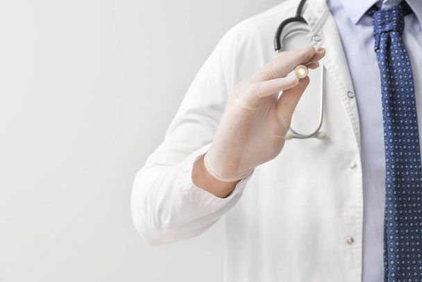 Médico masculino con linterna sobre fondo gris, primer plano
 - Foto, imagen