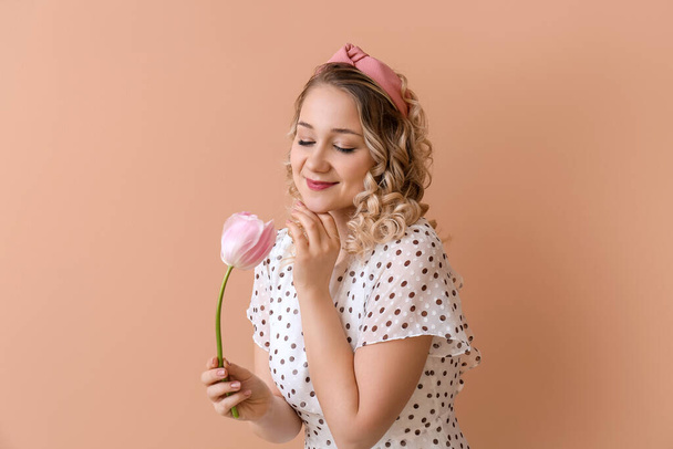 Mooie jonge vrouw met bloem op kleur achtergrond - Foto, afbeelding