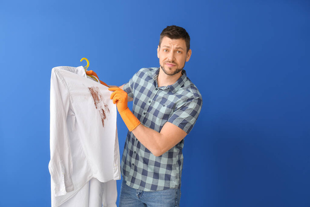 Displeased man with dirty clothes on color background - Foto, afbeelding