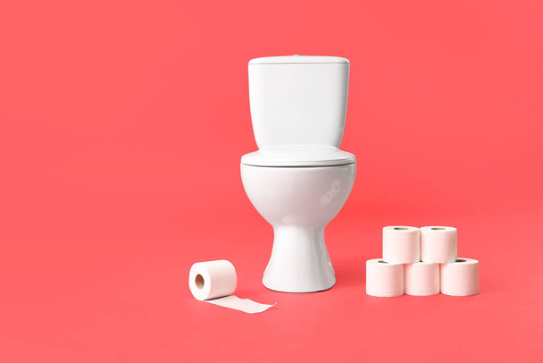 Toilettenschüssel mit Papierrollen auf farbigem Hintergrund - Foto, Bild