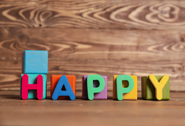 Kubussen en woord HAPPY op houten tafel - Foto, afbeelding