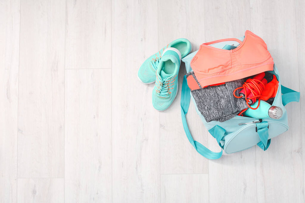 Bag with sportswear, equipment and shoes on wooden background - Photo, Image