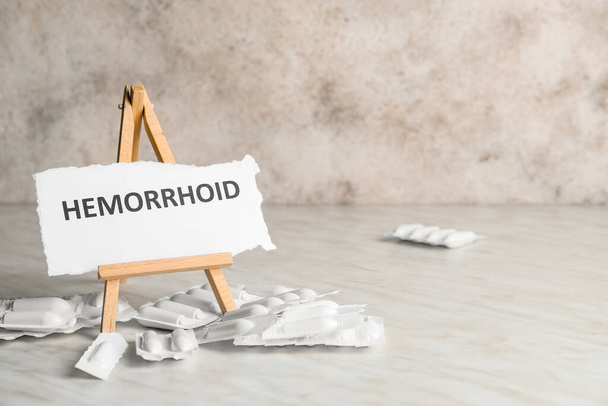 Supositórios hemorroidários e papel com palavra HEMORRHOID sobre fundo claro
 - Foto, Imagem