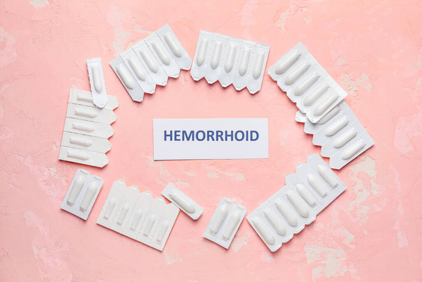 Υπόθετα και χαρτί με τη λέξη HEMORRHOID στο φόντο χρώματος - Φωτογραφία, εικόνα
