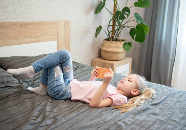 Happy cute little girl playing games on smartphone at home - Фото, зображення