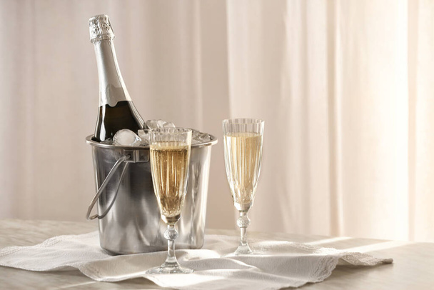 Bucket with ice and champagne on table in room - Photo, Image