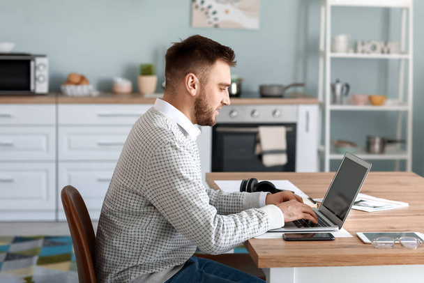 Молодий чоловік з ноутбуком працює вдома
 - Фото, зображення