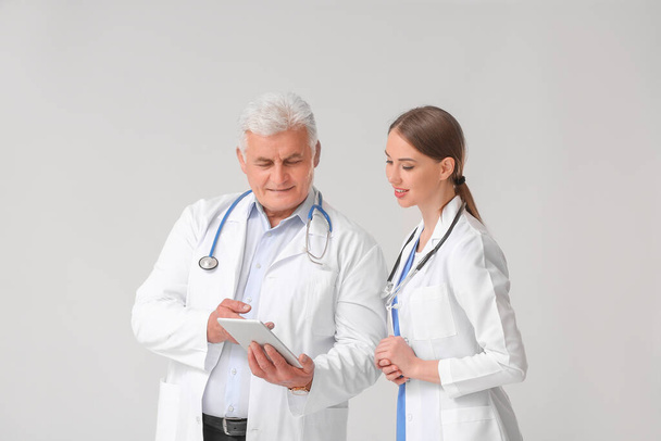 Лікарі з планшетним комп'ютером на сірому фоні
 - Фото, зображення