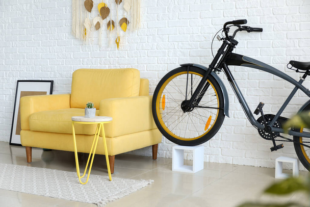 Интерьер современной гостиной с удобным креслом и велосипедом - Фото, изображение