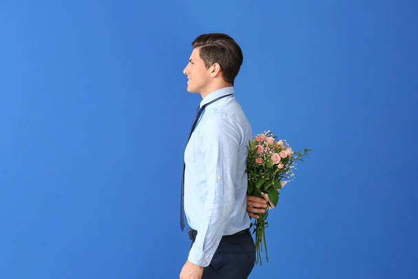 Hombre guapo con ramo de flores sobre fondo de color
 - Foto, imagen