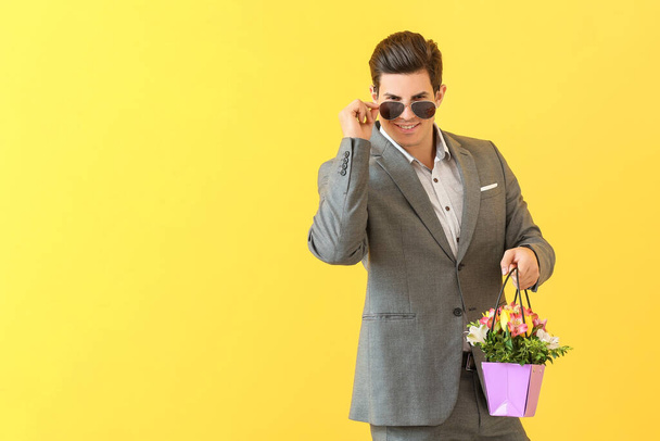 Handsome man with bouquet of flowers on color background - Fotografie, Obrázek