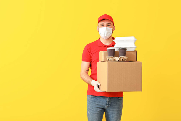 Male courier in medical mask on color background - Photo, Image