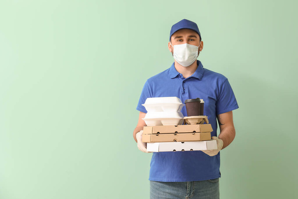 Mężczyzna kurier firmy dostarczania żywności w masce medycznej na tle koloru - Zdjęcie, obraz