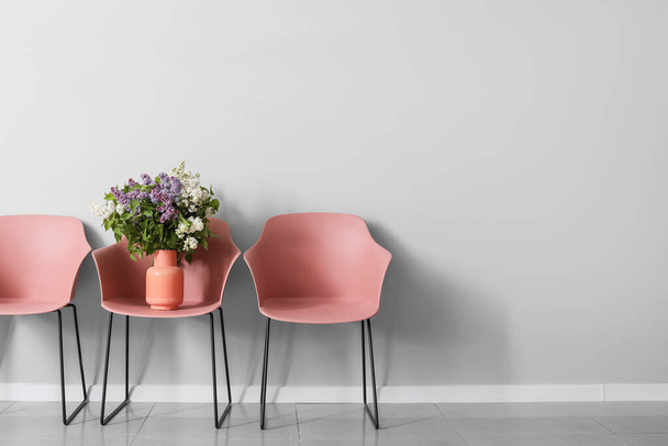 Stylish armchairs with beautiful lilac flowers near grey wall - Fotografie, Obrázek