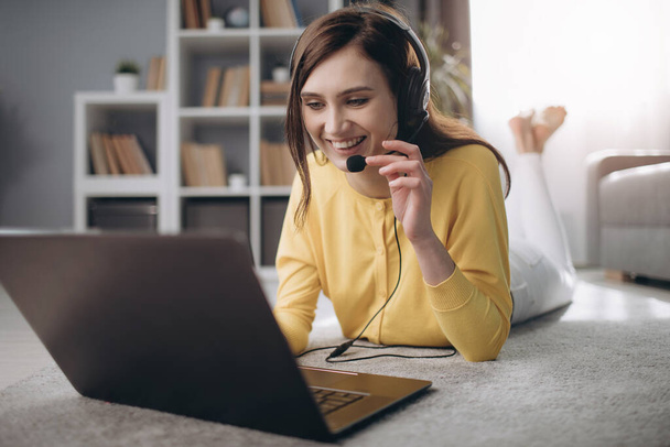 Uśmiechnięta dziewczyna w słuchawkach mając wideo czat na laptopie - Zdjęcie, obraz