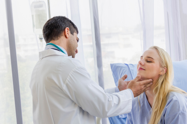 homme médecin examiné la douleur au cou d'une patiente assise dans le lit d'hôpital
 - Photo, image