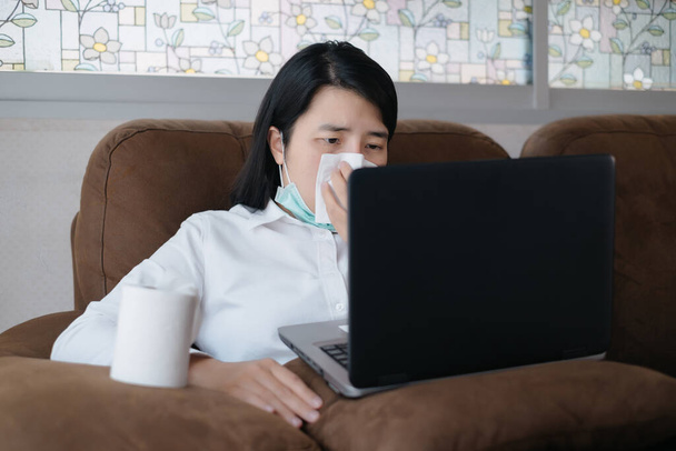 Больные азиатки, работающие из дома с ноутбуком и чихающие бумагой
 - Фото, изображение