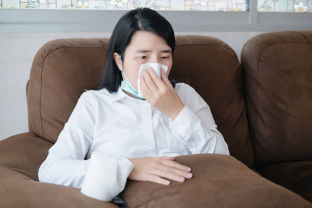 Las mujeres enfermas se sientan en la sala de estar y estornudan con papel tisú
  - Foto, imagen