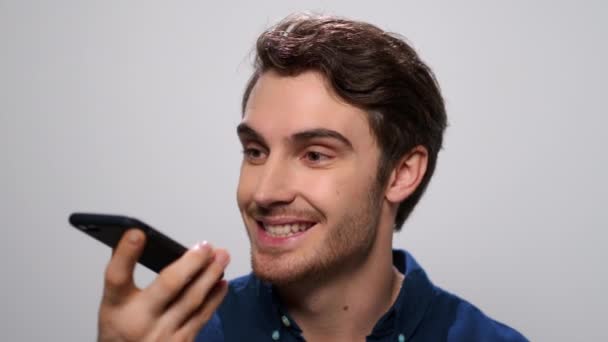 Lächelnder Mann, der Sprachnachrichten auf seinem Smartphone aufzeichnet. Glücklicher Mann mit Handy - Filmmaterial, Video