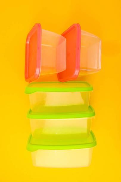 Lunchboxen aus Kunststoff auf gelbem Hintergrund, Bunte Plastikbehälter, leere Plastikbehälter mit bunten Deckeln - Foto, Bild