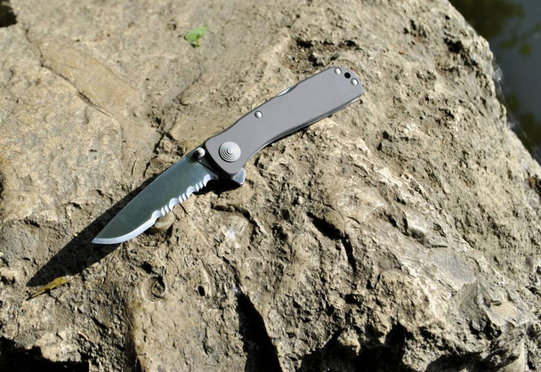 Folding knife stainless steel sharp blade gray aluminum handle close up still life nature stone background - Photo, Image