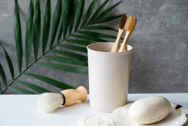 Eco friendly bathroom accessories on table. Natural wooden toothbrushes, shaving brush, organic soap. Minimalist nordic scandinavian style. Zero waste, sustainable lifestyle concept - Fotoğraf, Görsel
