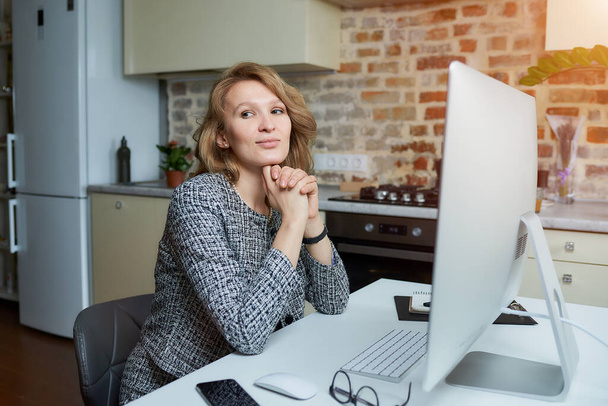 Bir kadın gülümsüyor ve stüdyosundaki masaüstü bilgisayarında uzaktan çalışıyor. Bir bayan evdeki bir video konferansı sırasında kollarını kavuşturur. Bir bayan profesör online bir derste öğrencinin cevaplarını dinliyor. - Fotoğraf, Görsel