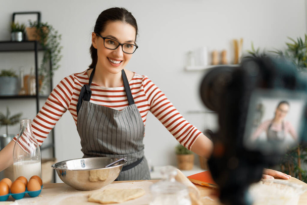 Young confident woman is talking on digital camera recording vlog about cooking. - Fotoğraf, Görsel