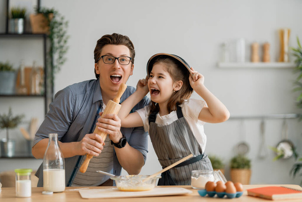 Happy loving family are preparing bakery together. Father and child daughter girl are cooking cookies and having fun in the kitchen. Homemade food and little helper.  - Foto, immagini