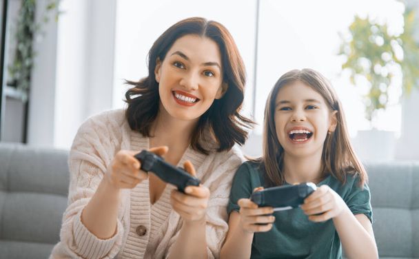 Happy family together. Mother and her child girl playing video games. People having fun at home. - Foto, Imagem