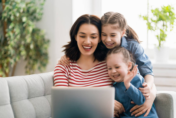 Happy loving family. Young mother and daughters girls using laptop. Funny mom and lovely children are having fun staying at home.  - Fotoğraf, Görsel