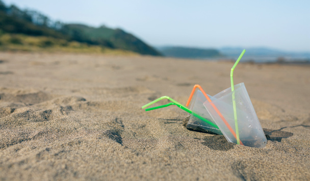 Spiaggia con bicchieri di plastica e cannucce
 - Foto, immagini
