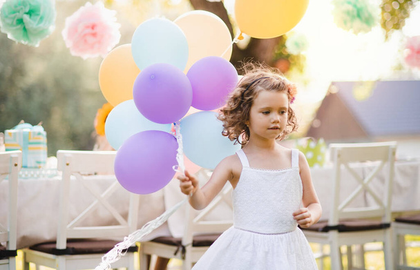 Portrait of small girl playing with balloons outdoors on garden party in summer. - Fotó, kép