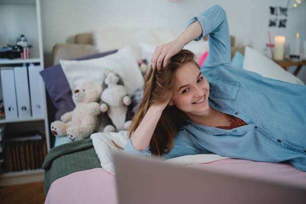 Beautiful happy young girl with laptop sitting and smiling, online dating concept. - Foto, afbeelding