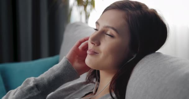Portrait of relaxed woman listening music in earphones - Кадри, відео
