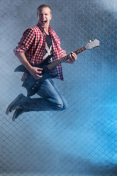Fiatal, őrült zenész elektromos gitárral - Fotó, kép