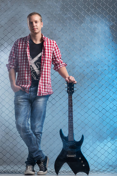 Musik, Klang. Musiker mit Gitarre auf Zaunhintergrund - Foto, Bild