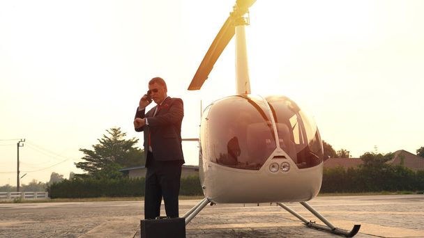 Empresario hablando por celular cerca de helicóptero privado - Foto, imagen