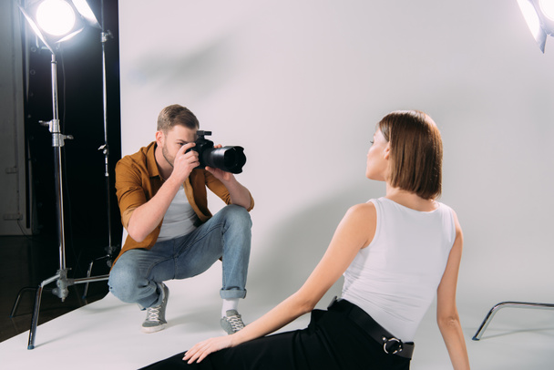 Model poseren terwijl fotograaf het nemen van foto 's op digitale camera in fotostudio  - Foto, afbeelding