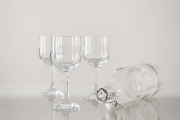 Prázdné sklenice na víno a láhev s vodou na skleněném stole. Skleněné zboží pro catering - Fotografie, Obrázek