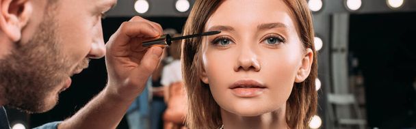 Panoramic shot of makeup artist applying mascara on beautiful model  - 写真・画像