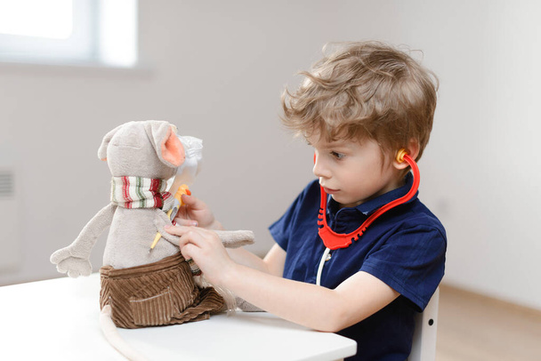 A little boy plays a doctor and measures the temperature with a thermometer toy rat. Detects coronavirus in toys. - Foto, Imagem