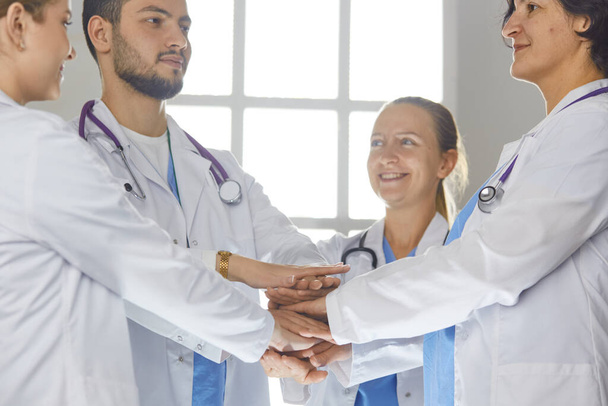 Ομάδα ιατρών κρατιούνται χέρι-χέρι σε εσωτερικούς χώρους, πάνω από την άποψη. Έννοια ενότητας - Φωτογραφία, εικόνα