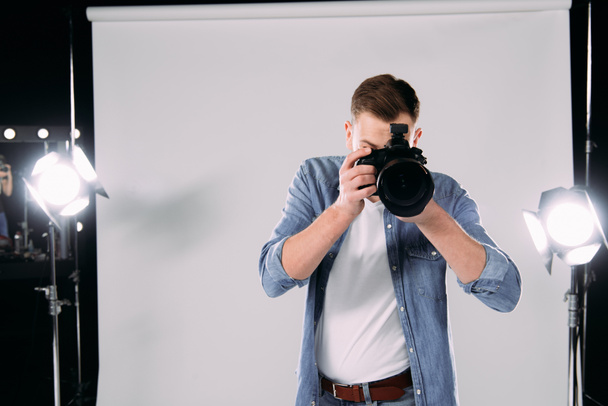 Photographer taking photo with digital camera in photo studio  - Foto, immagini