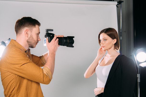 Handsome photographer working with beautiful young model in photo studio  - Foto, afbeelding