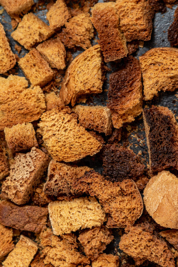 Burnt bread crackers. The texture of the slices of dry rye bread. Crackers or rusks made from homemade white bread are baked in the oven in close-up. Cooking croutons. - Photo, Image
