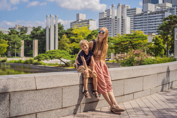 Coronavirus is over. Quarantine weakened. Take off the mask. Now you can go to public places. Mom and son tourists in Korea. Travel to Korea concept. Traveling with children concept - Foto, Imagem