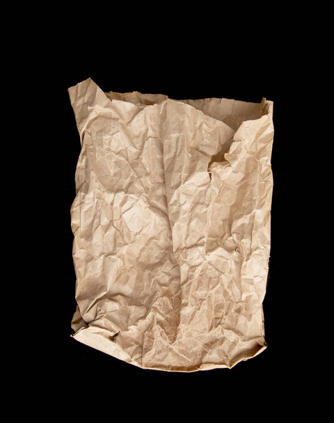 Una bolsa de papel arrugada con manchas grasas aisladas sobre un fondo negro
 - Foto, imagen