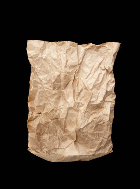 A crumpled paper bag with greasy spots isolated on a black background - Fotoğraf, Görsel